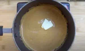 Creamy peanut butter sauce in a saucepan with melting butter, perfect for savory recipes.